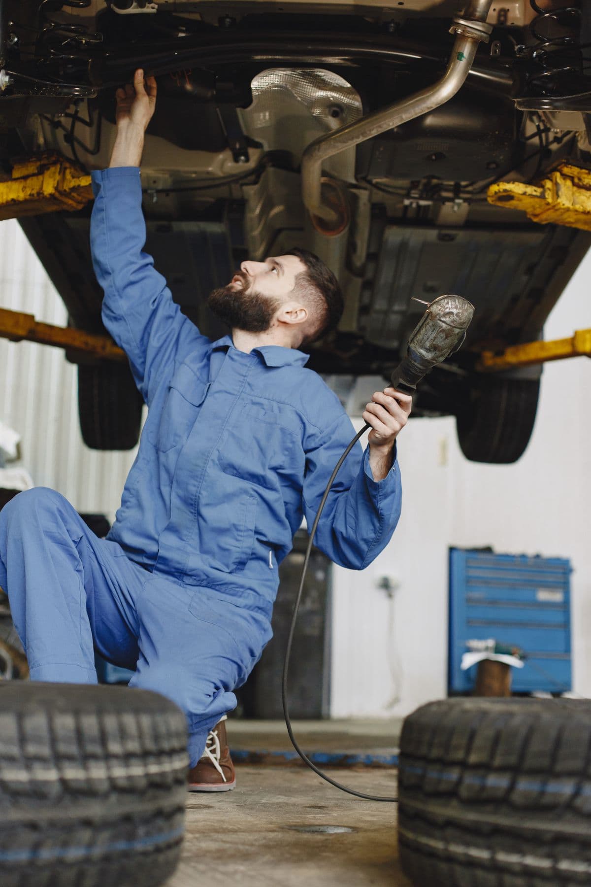 Mechanic inspecting brakes beneath a raised vehicle