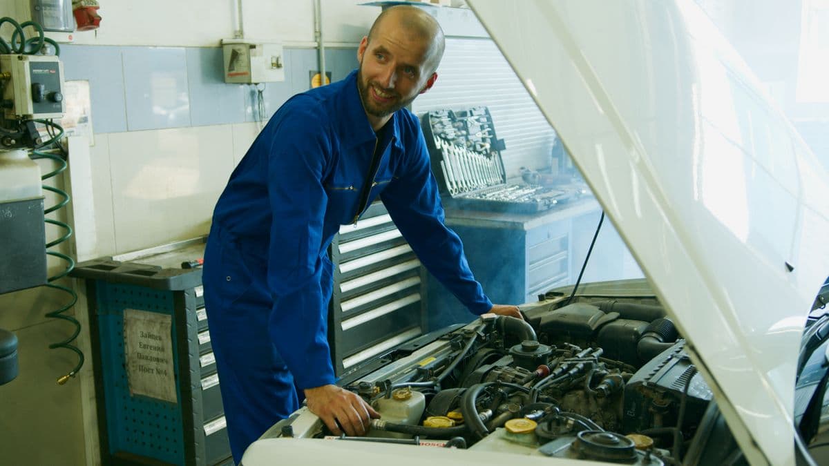 Technician checking an engine bay with the hood raised