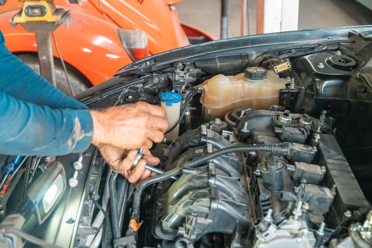 Hands working in an open engine bay